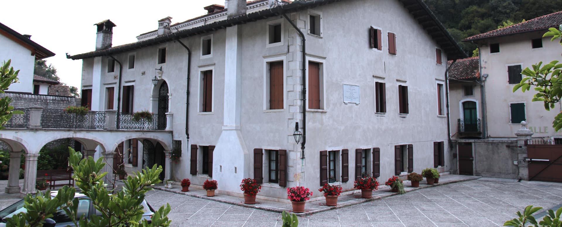 La facciata di Palazzo Scolari sulla piazza di Polcenigo, con i gerani rossi