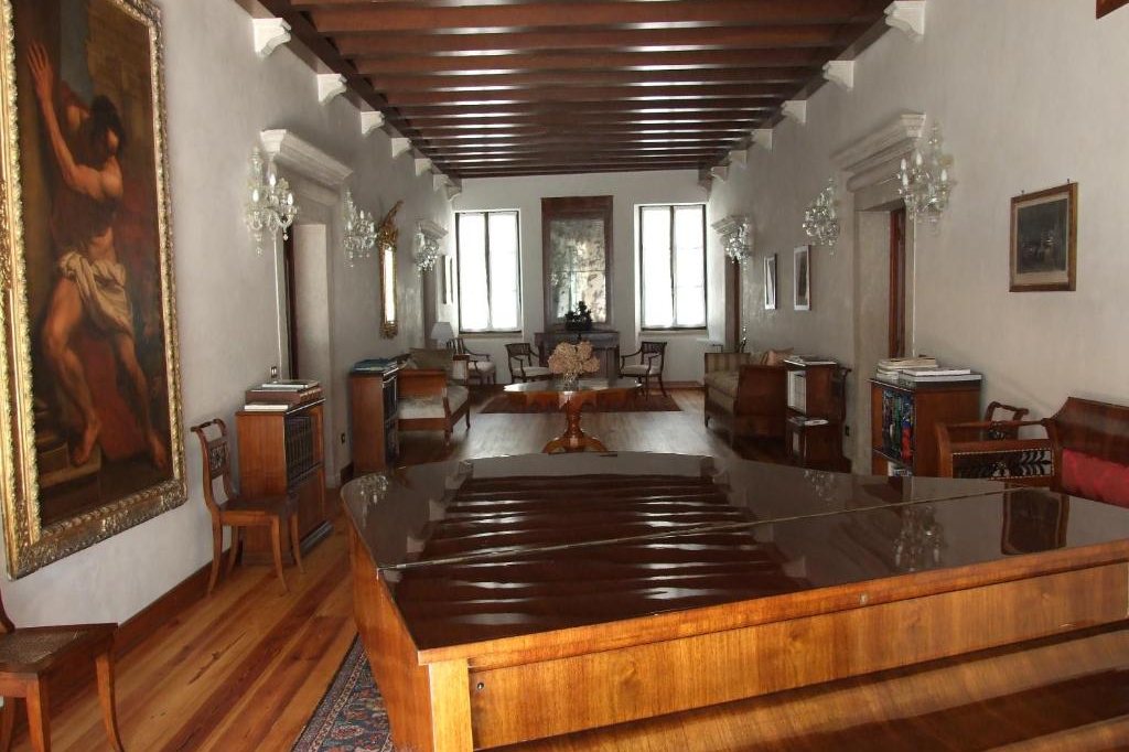Il salone del primo piano visto per il lungo: il quadro del Sansone, il soffitto a travi e il pianoforte a coda in primo piano